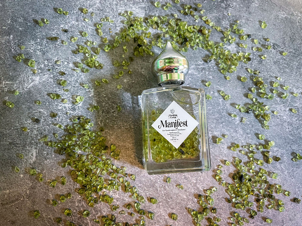Manifest Perfume Oil For Manifestation with Peridot and Sage with Peridot crystals around the bottle.