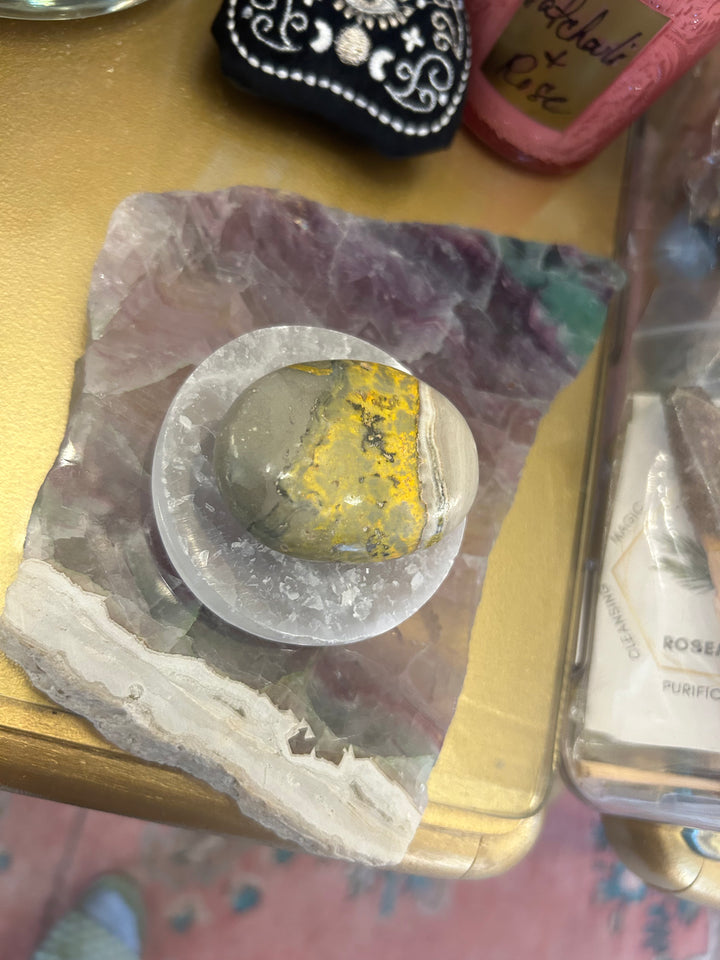 Small Selenite Charging Plate under a fluorite plate and has a bumble bee palm stone on top