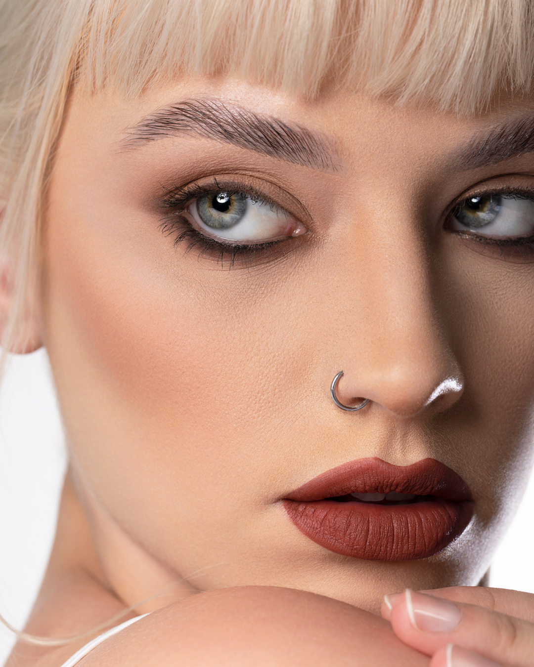 A model wearing the Peaking Velvet Mousse Lipstick which is like a darker more mysterious red