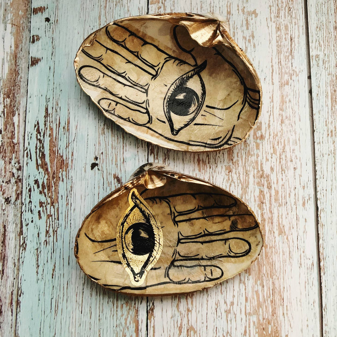 This is a shell hand painted with a brown base and an eye in the middle of the hand.
