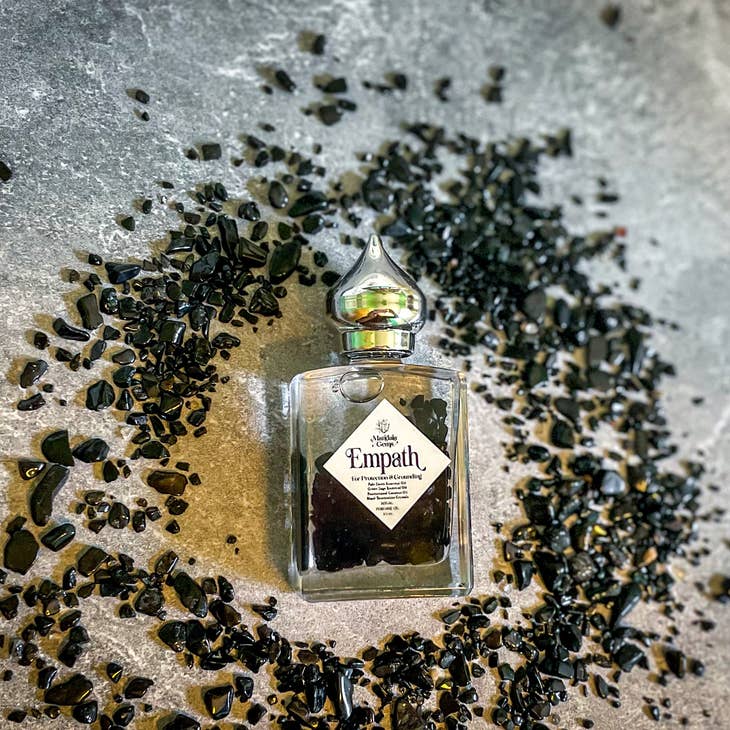 Empath Protection Crystal Infused Perfume Oil with Black Tourmaline with the crystal around the bottle