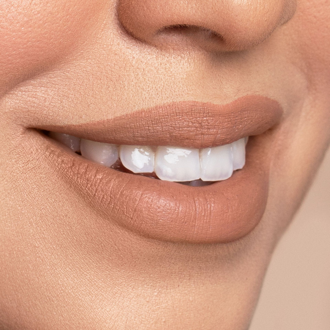 A close up of the cozy lip shade on this models lips. It is a beautiful warm nude with an orange undertone.