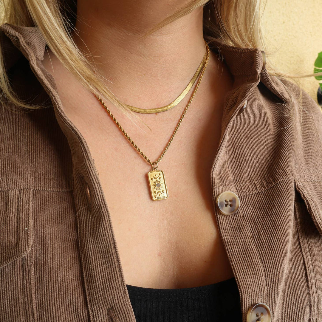 The Sun' Tarot Card Necklace on a model with a darker outfit that has a jacket