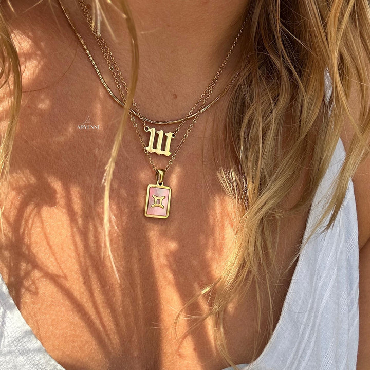 one of the zodiac necklaces on a model stacked with others