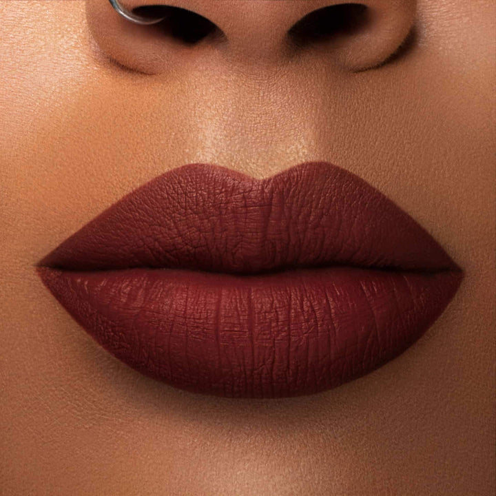 This is a medium skin tone lip swatch of the Brick Liquid Matte Lip.