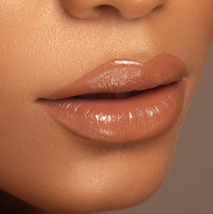 This is a model wearing the Don't Be Chai Lip Gloss. You can see the nude with the glossy shimmer.