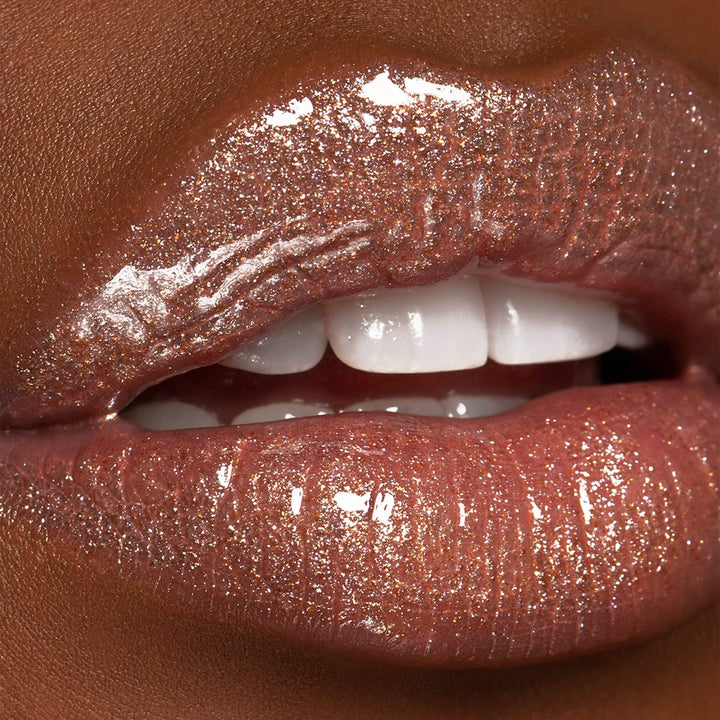 This is a model with a darker skin tone wearing the Jazzy Lip Gloss.