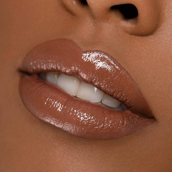 This is a model with a darker skin tone wearing the Moody Lip Gloss.