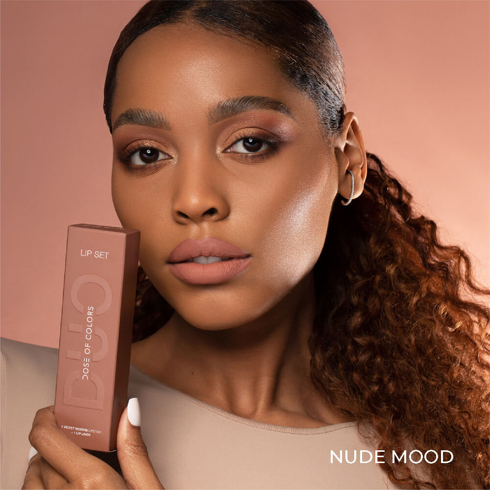 A model wearing the Nude Mood Velvet Mousse Lip Duo with her holding up the box next to the lips too