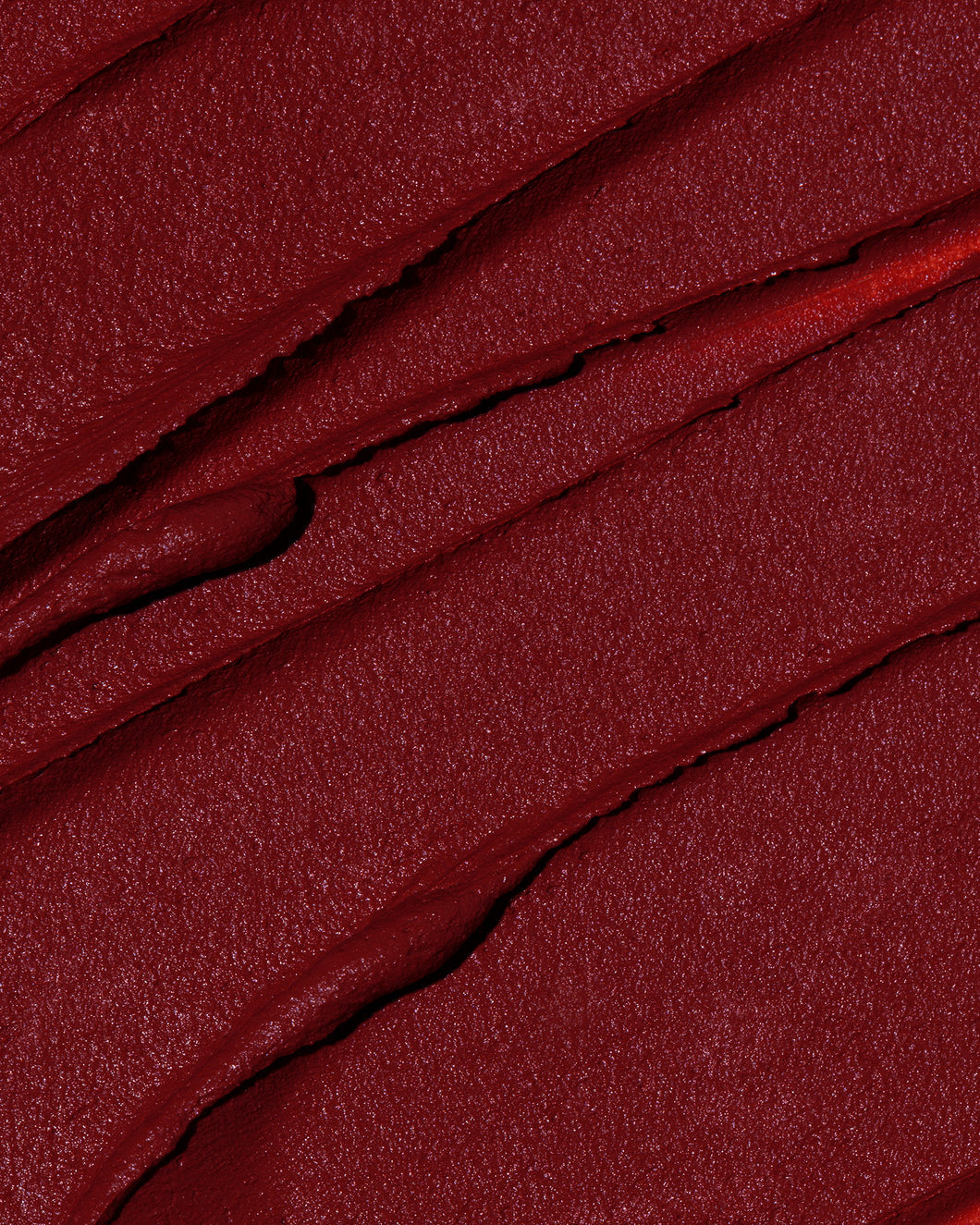 Swatch of the Out of office red Velvet Mousse Lipstick. This swatched looks like a dewy rose or shimmery curtain 