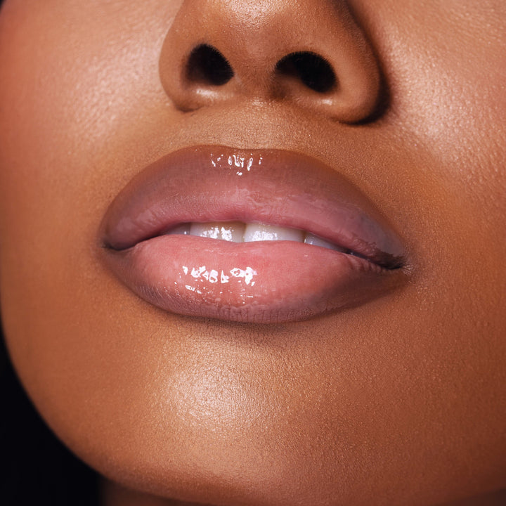 This is a Dark skin model wearing the Top Coat lip oil