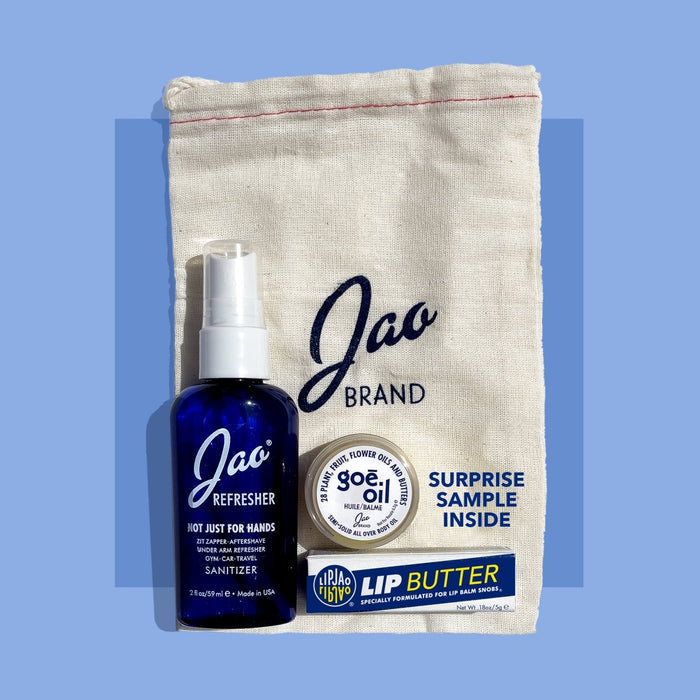 Jao Brand product set with a blue bottle, lip balm, and sample pouch on a blue background