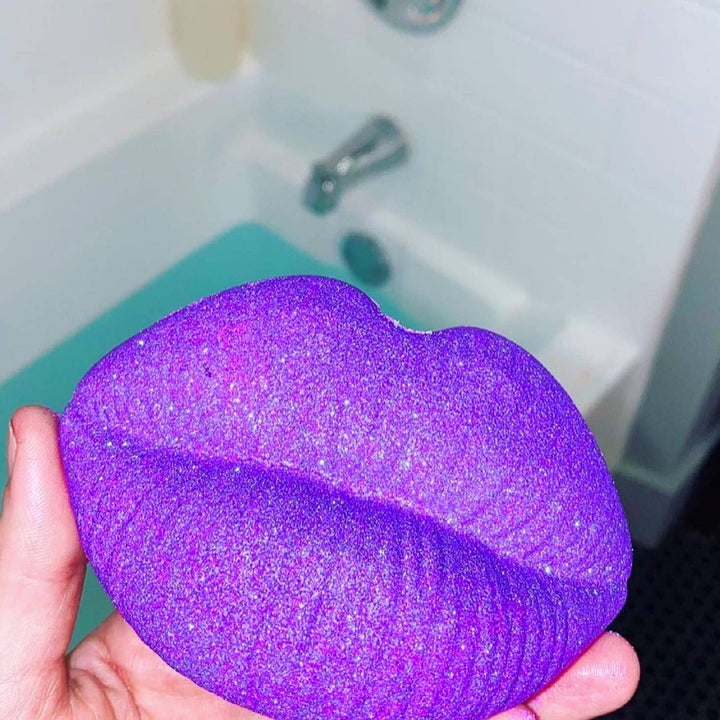 Purple bath bomb with bloodstone crystal insideMoon Kissed- Bloodstone Crystal Infused Bath Bomb in front of a bath