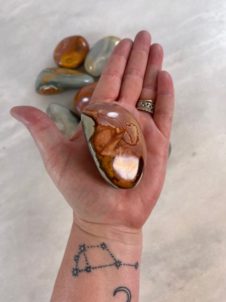 Large Polychrome/Desert Jasper Palm stone being held in the palm of a hand